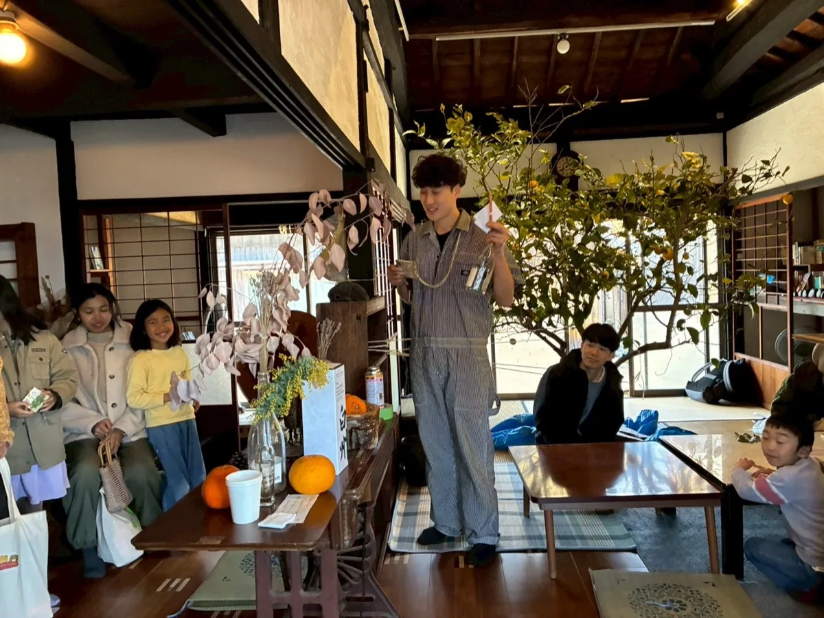 古民家の中で柑橘の木を囲み集う人々